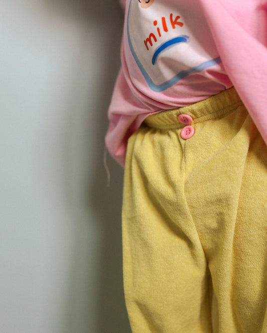 Person wearing a pink shirt with a milk carton design and yellow pants.
