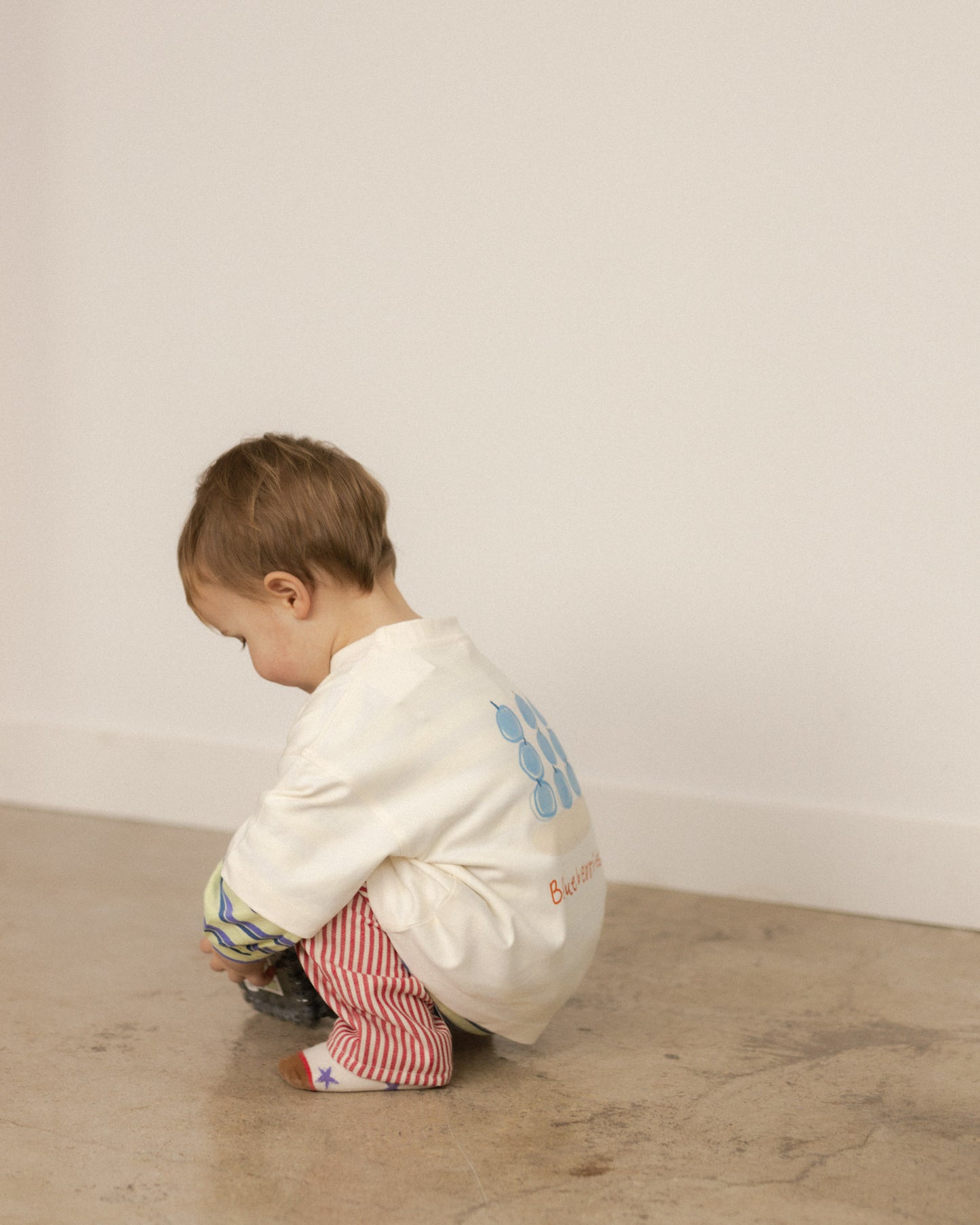 toddler wearing a blueberry shirt paired with red stripe pants and star socks