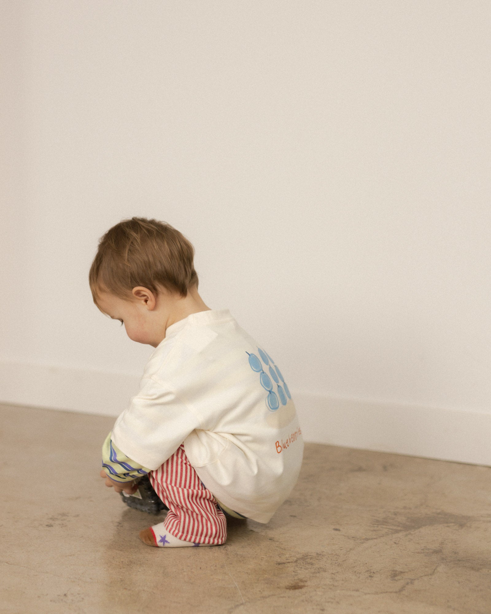 toddler wearing a blueberry shirt paired with red stripe pants and star socks