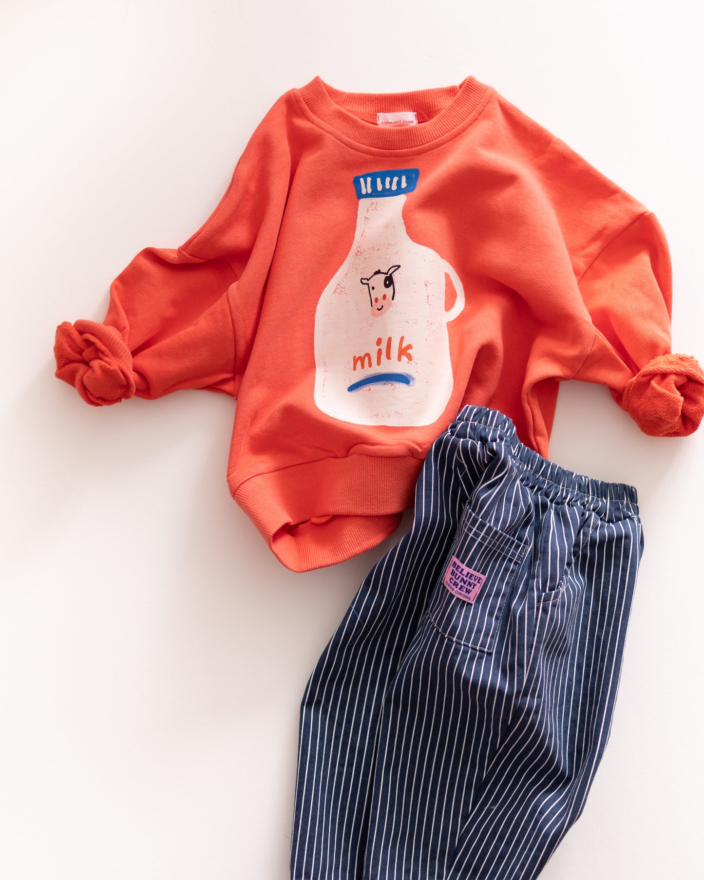 red sweatshirt with milk bottle design and blue striped pants on a white background