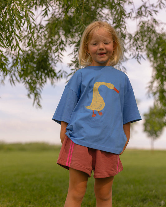 little girl wearing a blue graphic boxy tee with cute cotton track shorts 