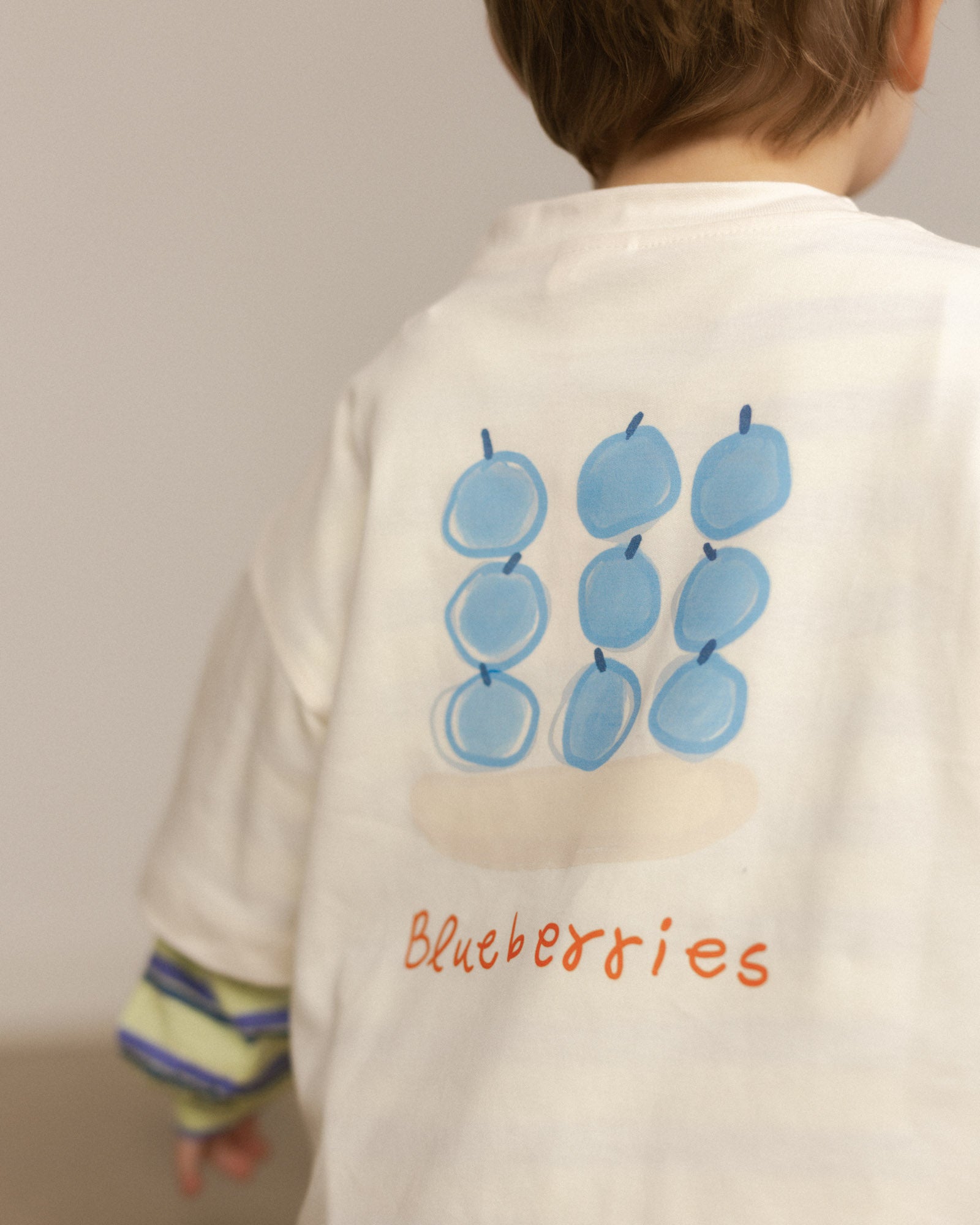 Child wearing a shirt with blueberry design and 'Blueberries' text