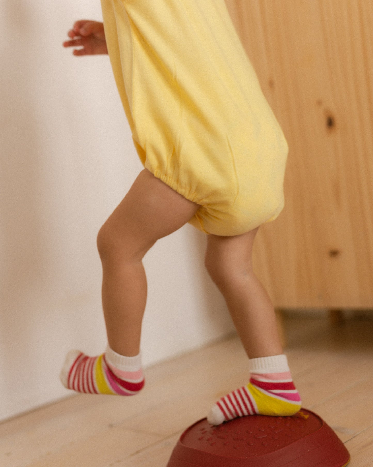 toddler wearing a yellow romper and colourful socks running around