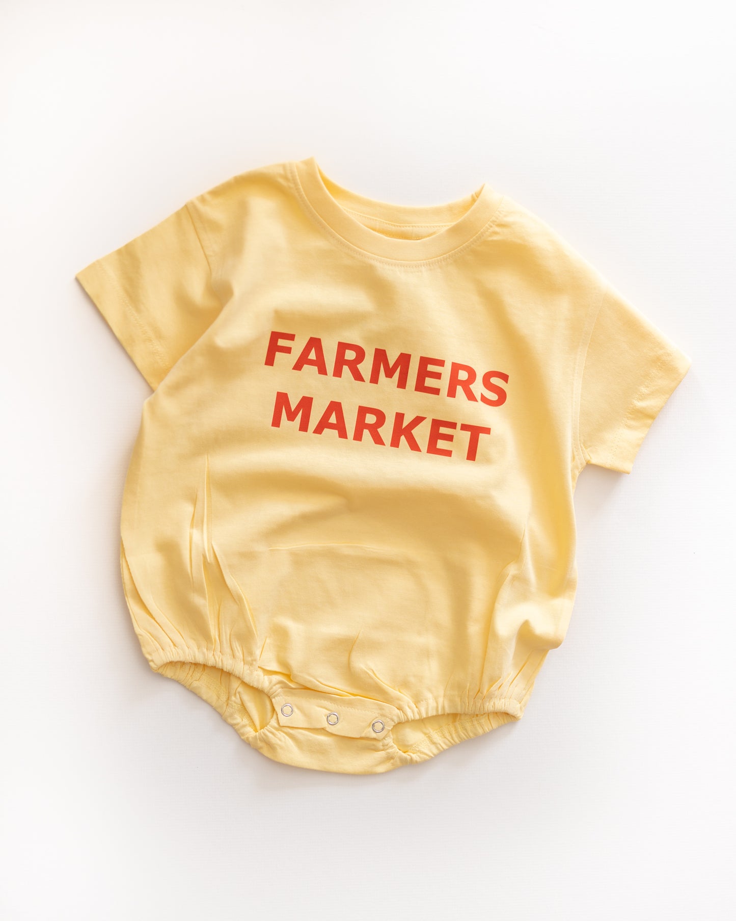 Yellow baby romper with 'Farmers Market' text on a white background