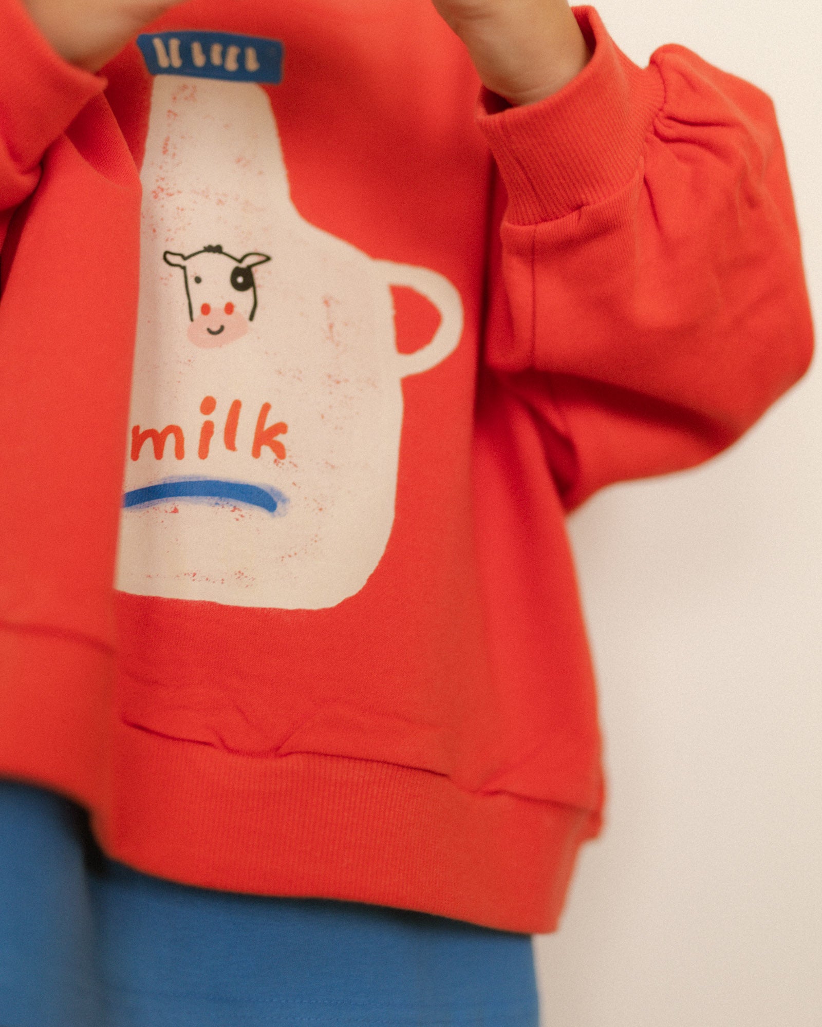 Red sweatshirt with a milk bottle graphic on a plain background