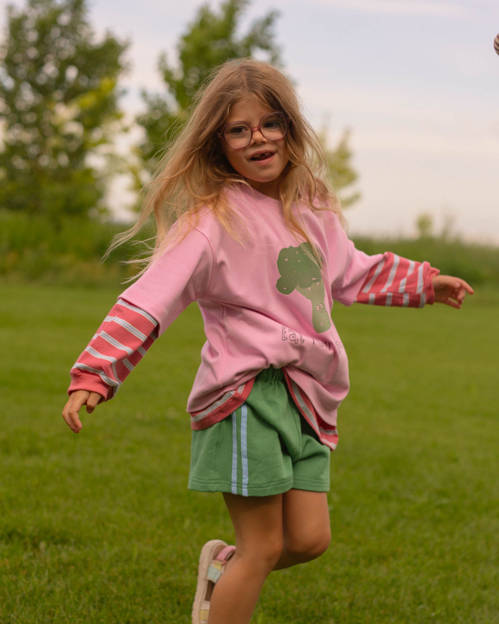 green and blue cotton track shorts, pink and blue striped long sleeve layered under a pink graphic tee