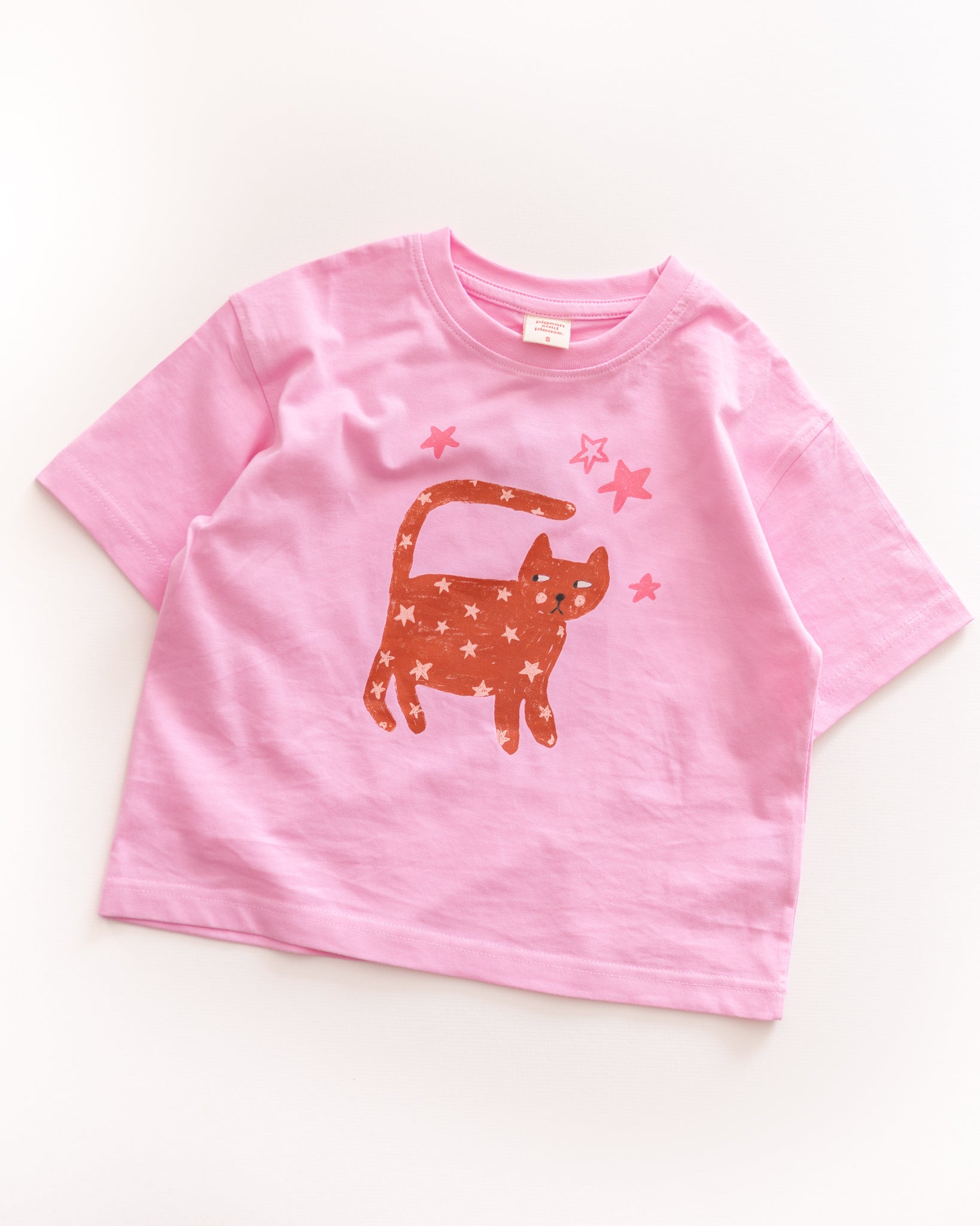 Pink t-shirt with a starry cat graphic on a white background
