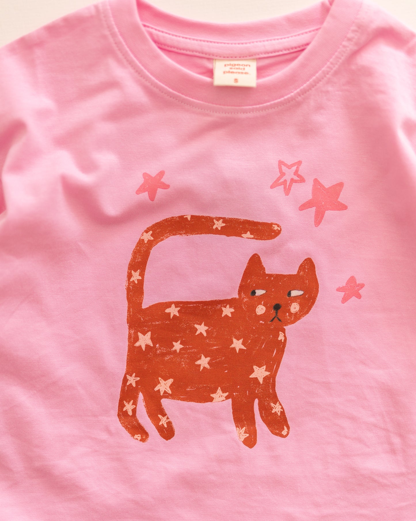 Pink t-shirt with a red cat design and star patterns