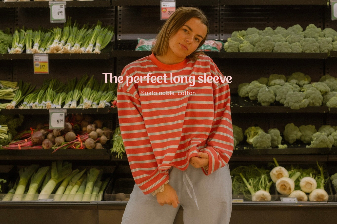 Person wearing a red and white striped long-sleeve shirt in a grocery store aisle with vegetables.