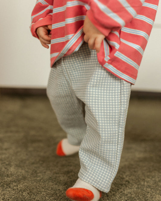 Person wearing a red and white striped shirt with checkered pants on a carpeted floor.