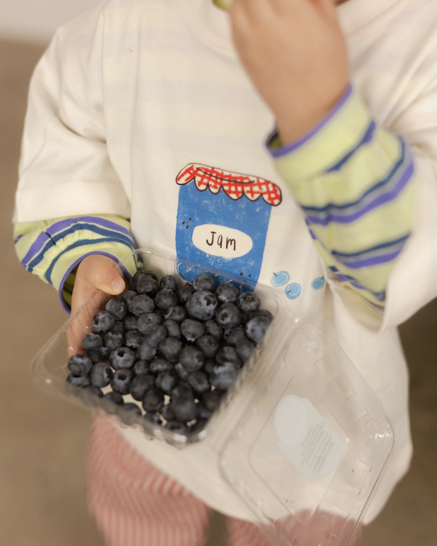 Child holding a container of blueberries with a  blueberry shirt 